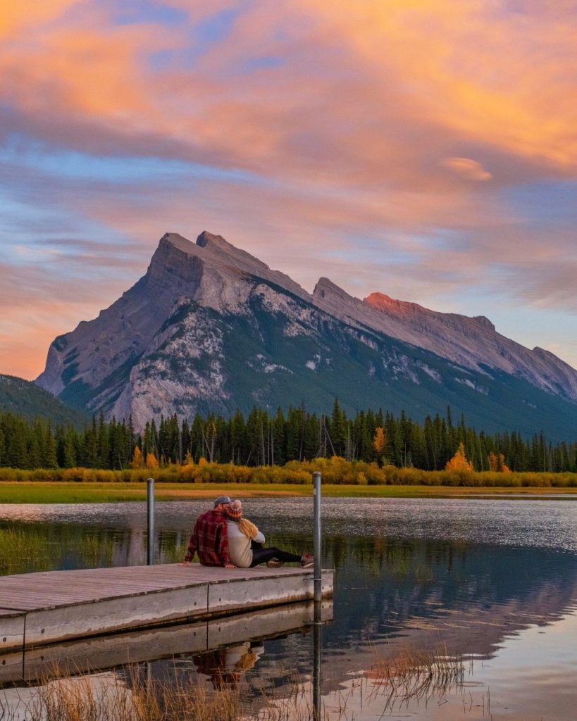 A tranquil sunset view of Mount Rundle rising above the calm waters of the Vermilion Lakes in Banff National Park.