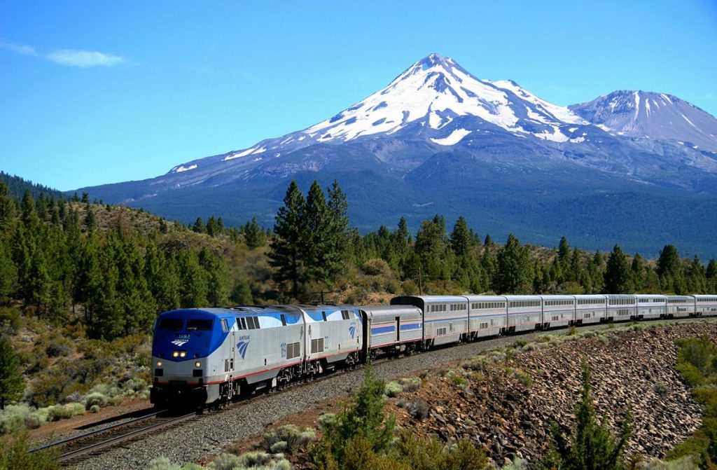 The Amtrak Coast Starlight train is shown passing Mount Shasta in California.