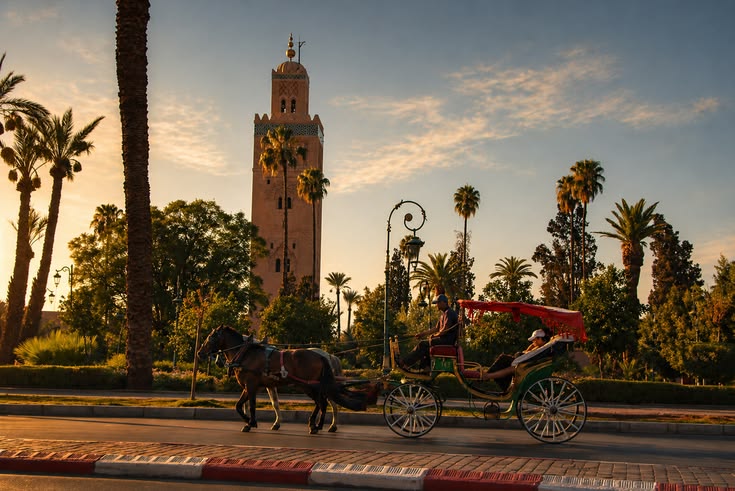 The Koutoubia Mosque minaret towering over a traditional horse-drawn carriage (calèche) near Jemaa el-Fnaa square in Marrakech, Morocco.