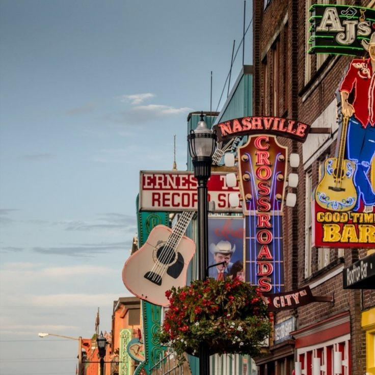 Lower Broadway in Nashville, Tennessee, famous for its live music clubs and vibrant nightlife, often referred to as "Music City," featuring neon signs for bars and music venues.