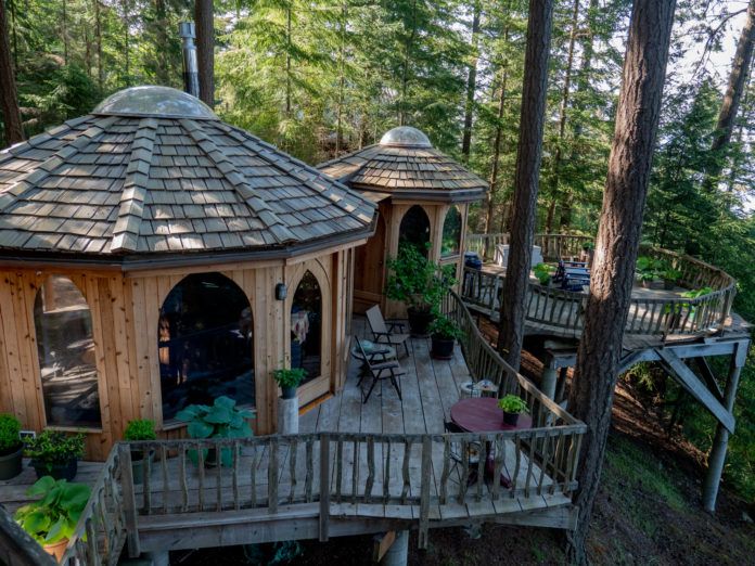 The unique, handcrafted "Forest House" on Orcas Island, designed by SunRay Kelley, featuring distinct rounded pods and expansive exterior decks for peaceful, secluded stays.