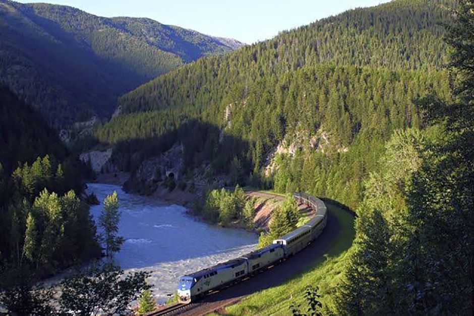 The Amtrak Empire Builder train traveling through the mountainous landscape of Glacier National Park in Montana.